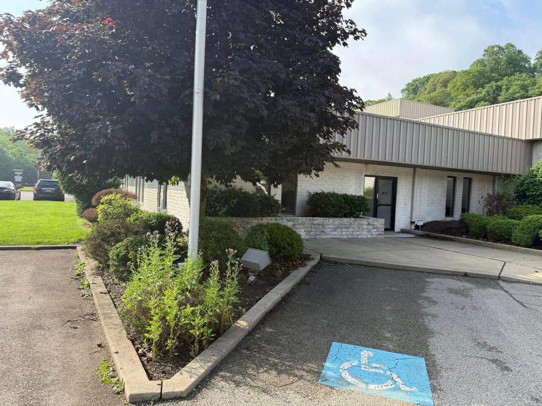 Handicap-accessible entrance of a commercial building with landscaping and a parking lot.
